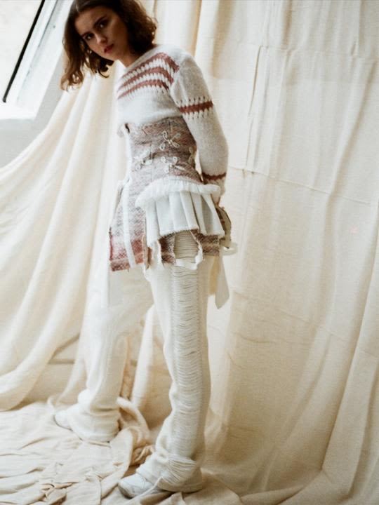 Model posing in a cream knitted jumper with matching laddered cream knit trousers