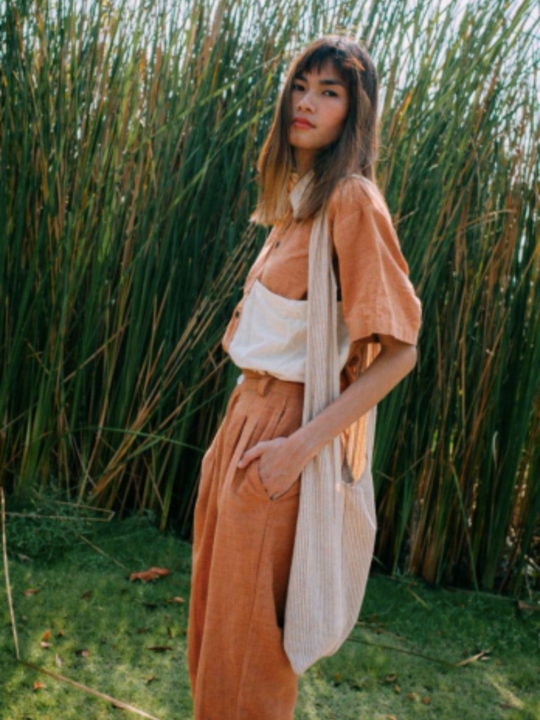 Model posing in a burnt orange short sleeved cotton shirt with matching trousers