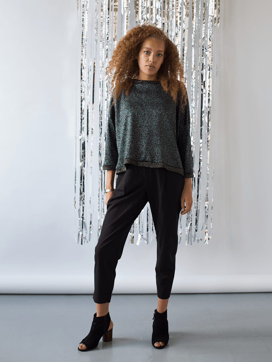 Model posing in dark grey glittery long sleeve top