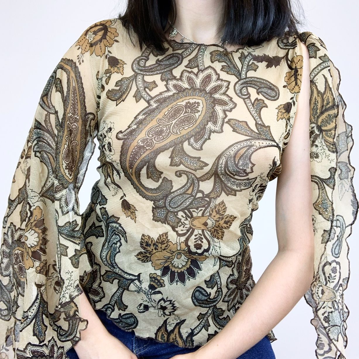 Emily posing in a sheer mesh floral top with flowy open sleeves
