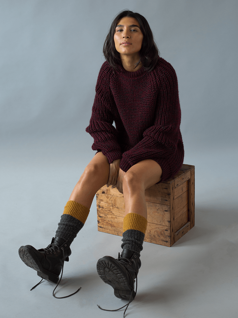 Model posing in a burgundy chunky knit sweater