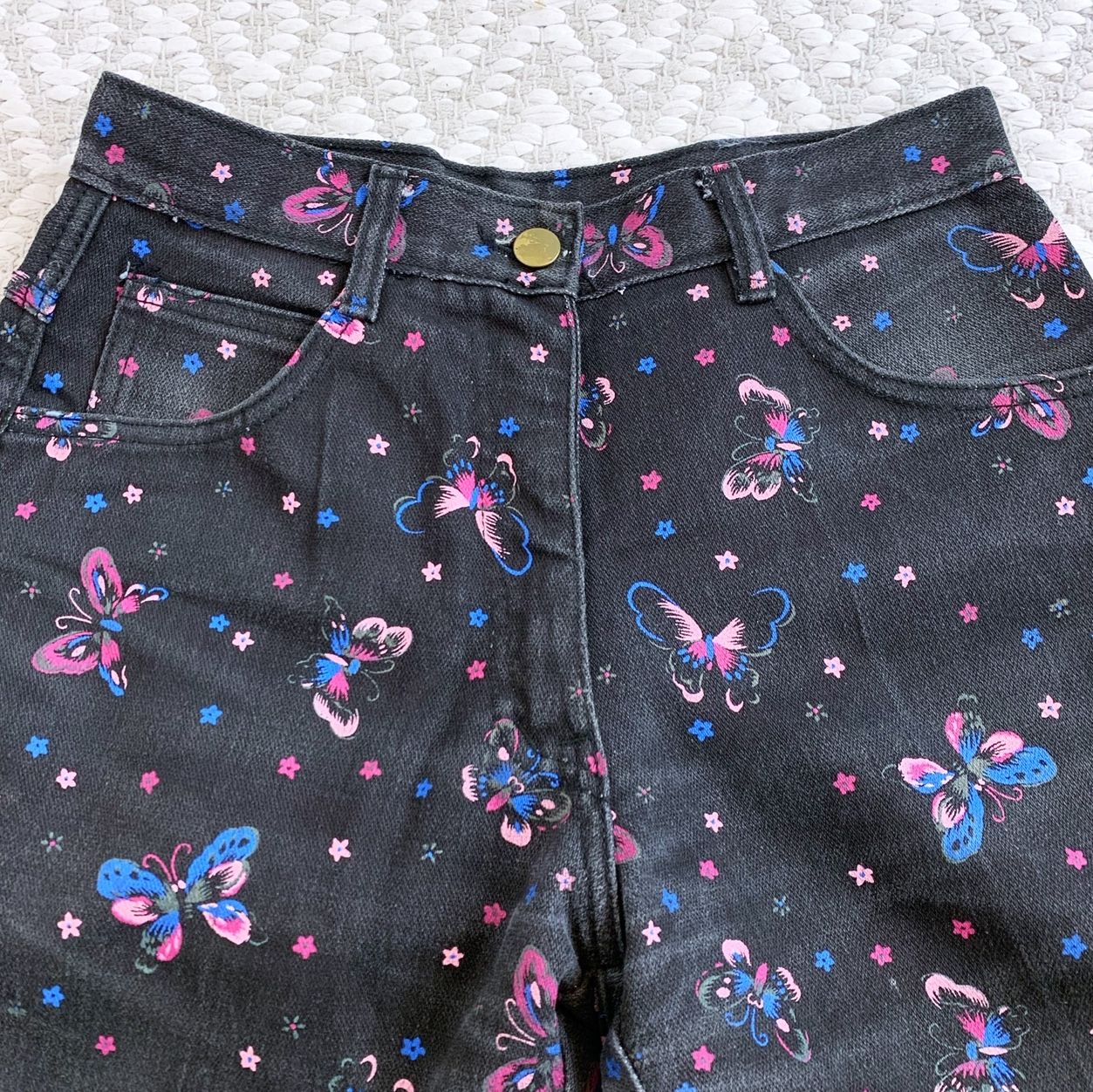 Close up picture of black mom jeans with a pink and blue floral butterfly pattern